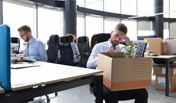 Sad dismissed worker are taking his office supplies with him from office.