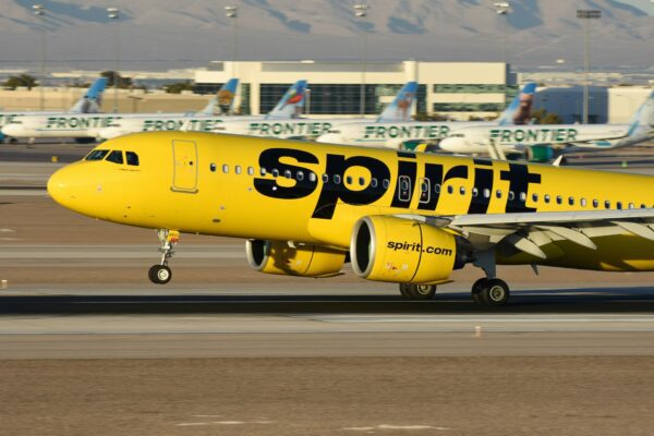 A yellow spirit airplane on the runway of an airport