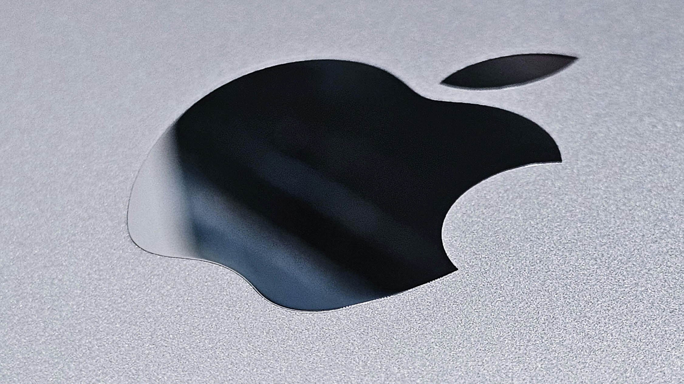 a close up of an apple logo on a silver surface