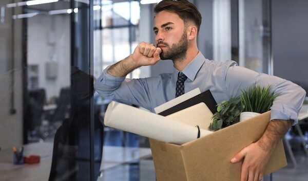 Sad dismissed worker is taking his office supplies with him from office.