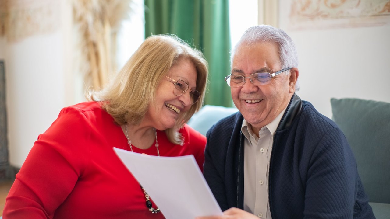 Older couple smiling while reading a letter together